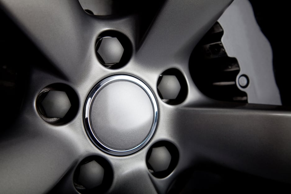 Picture of a black car tire with focus on nuts